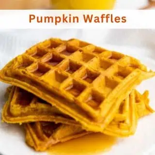 Two stacked pumpkin waffles covered in syrup on a white plate, with the words "Pumpkin Waffles" written above.