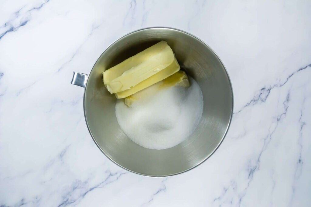 A bowl of butter and sugar on a marble surface.