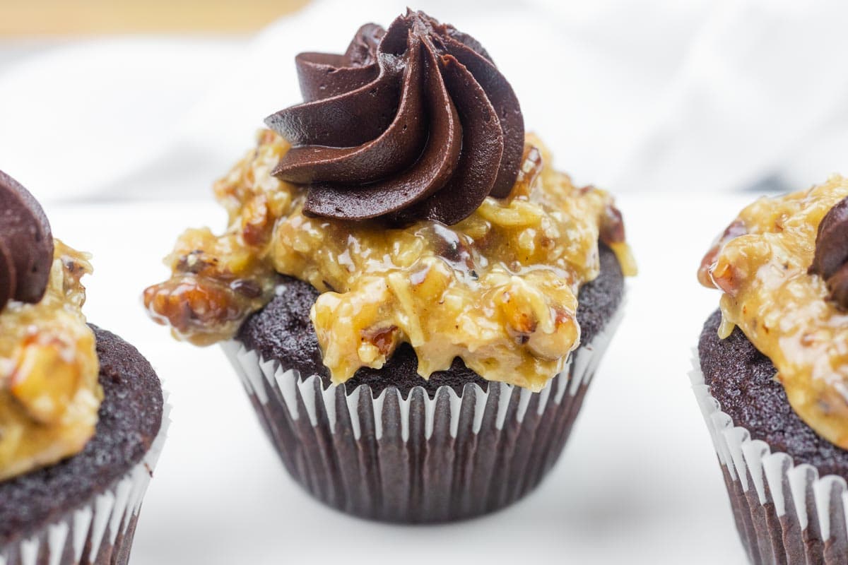 A close-up of German chocolate cupcakes topped with coconut-pecan frosting and a swirl of chocolate icing.
