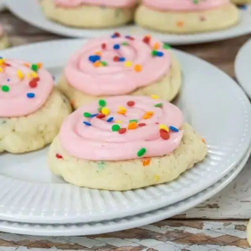Pink frosted sugar cookies on white plates.