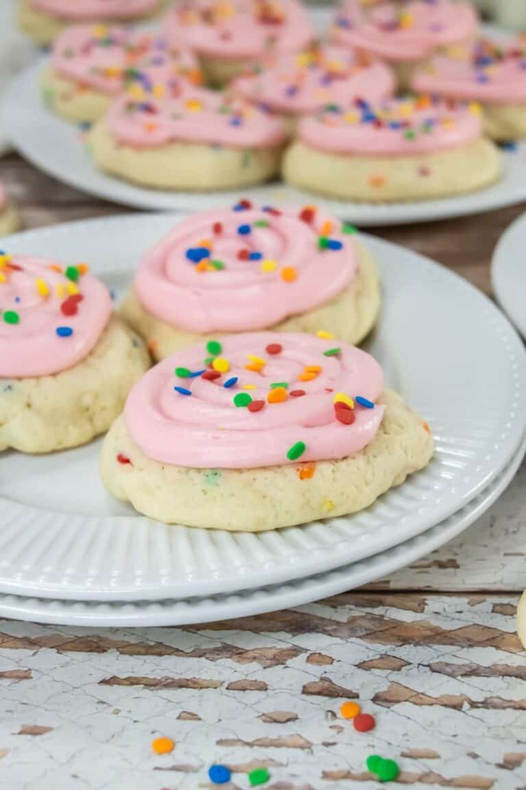 Pink frosted sugar cookies on white plates.