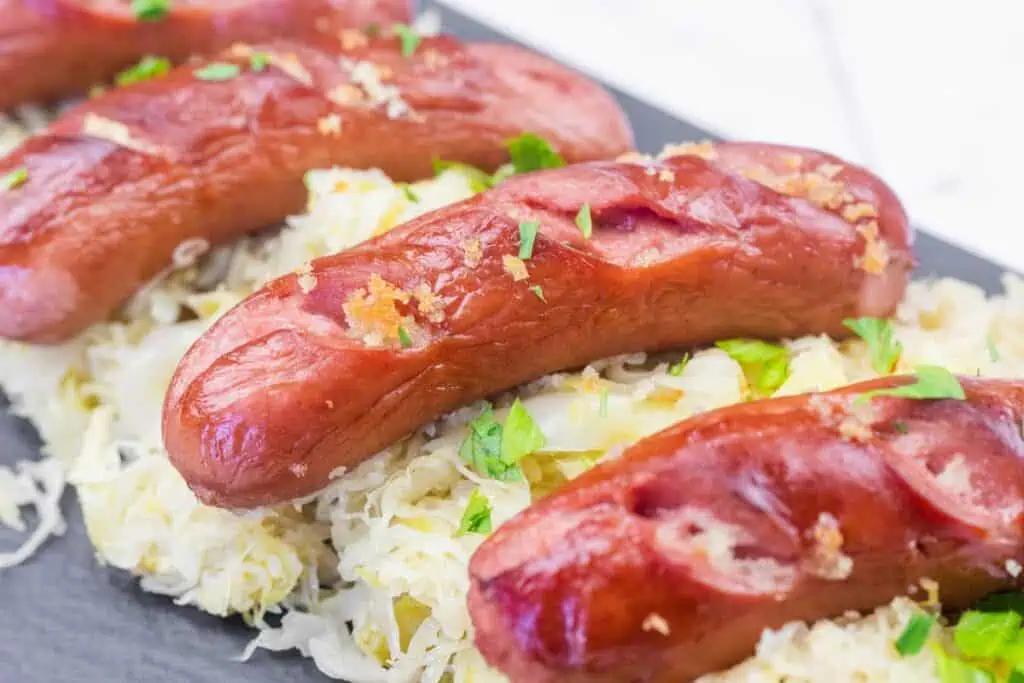 Grilled sausages served on a bed of sauerkraut, garnished with chopped parsley.