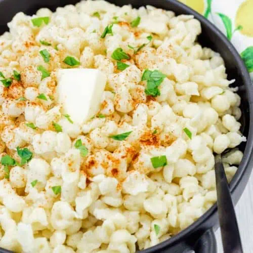 A black dish with a Spaetzle on a white wooden table.