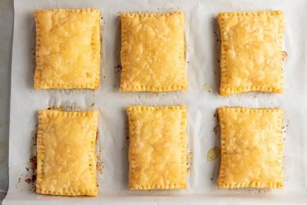 Six rectangular golden-brown pastries are arranged in two rows on a sheet of parchment paper.