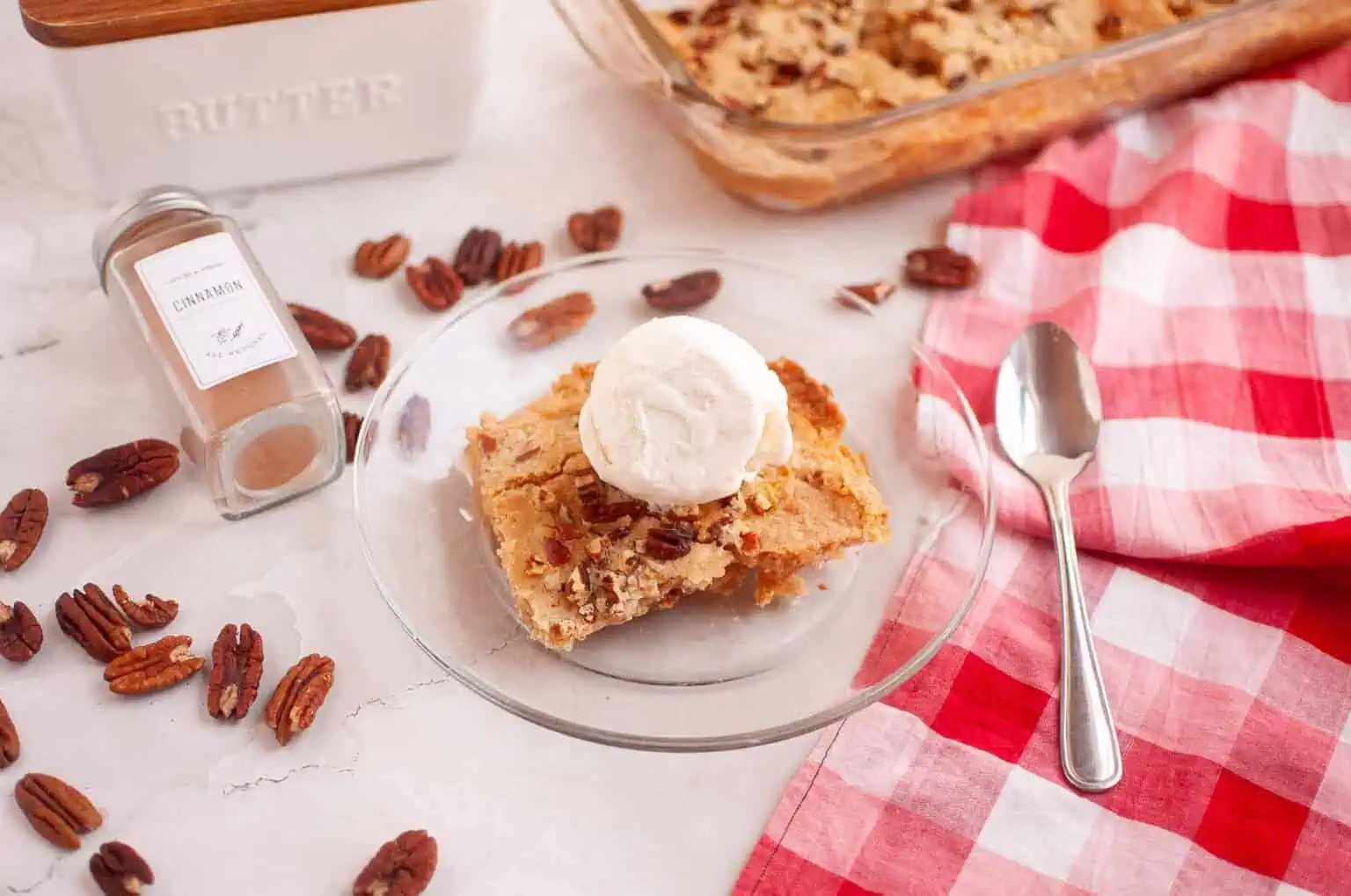 A square of Apple Dump Cake topped with a scoop of vanilla ice cream on a clear plate.