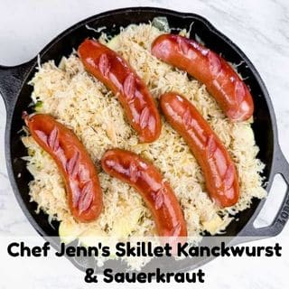 Five cooked knackwurst sausages on top of sauerkraut in a cast iron skillet, with text reading "Chef Jenn's Skillet Kanckwurst & Sauerkraut.