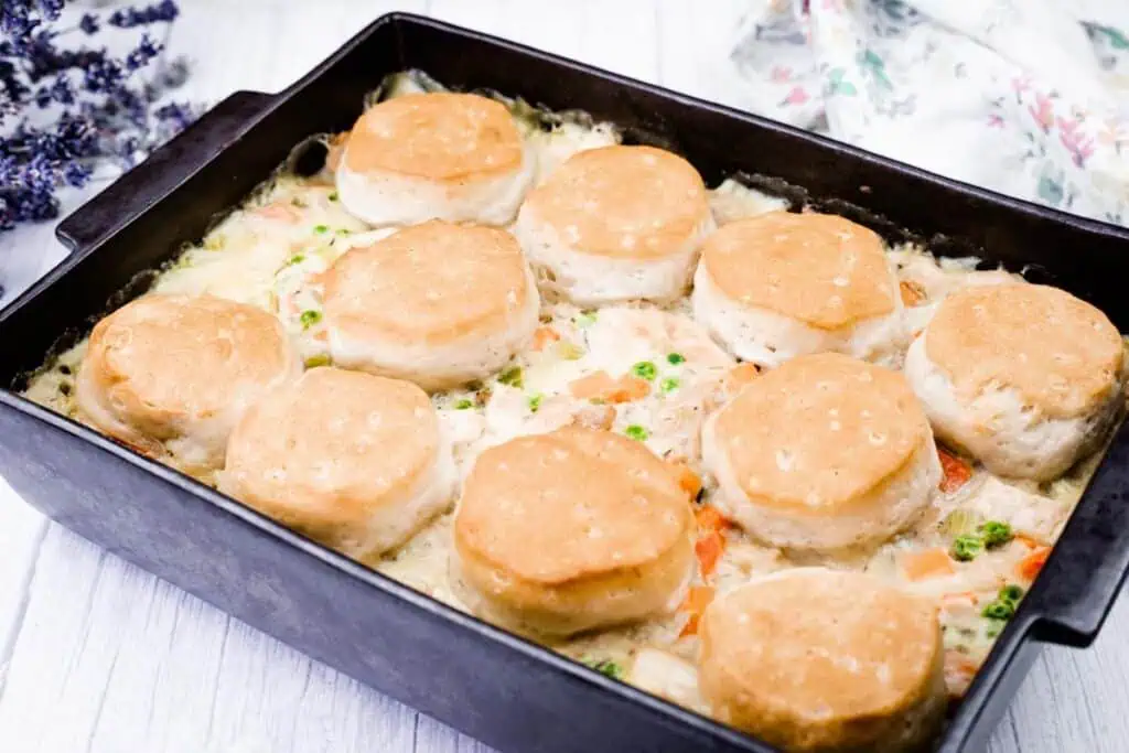 A casserole dish filled with creamy chicken and vegetables, topped with baked golden biscuits.