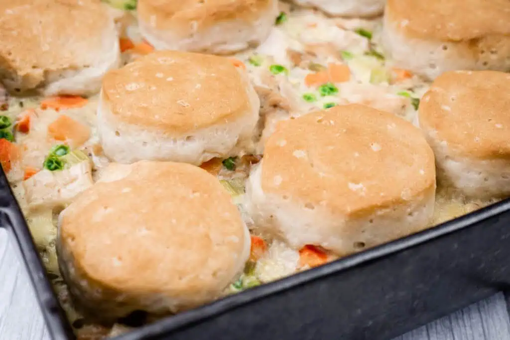 A baking dish filled with creamy chicken and vegetable casserole, topped with baked golden-brown biscuits.