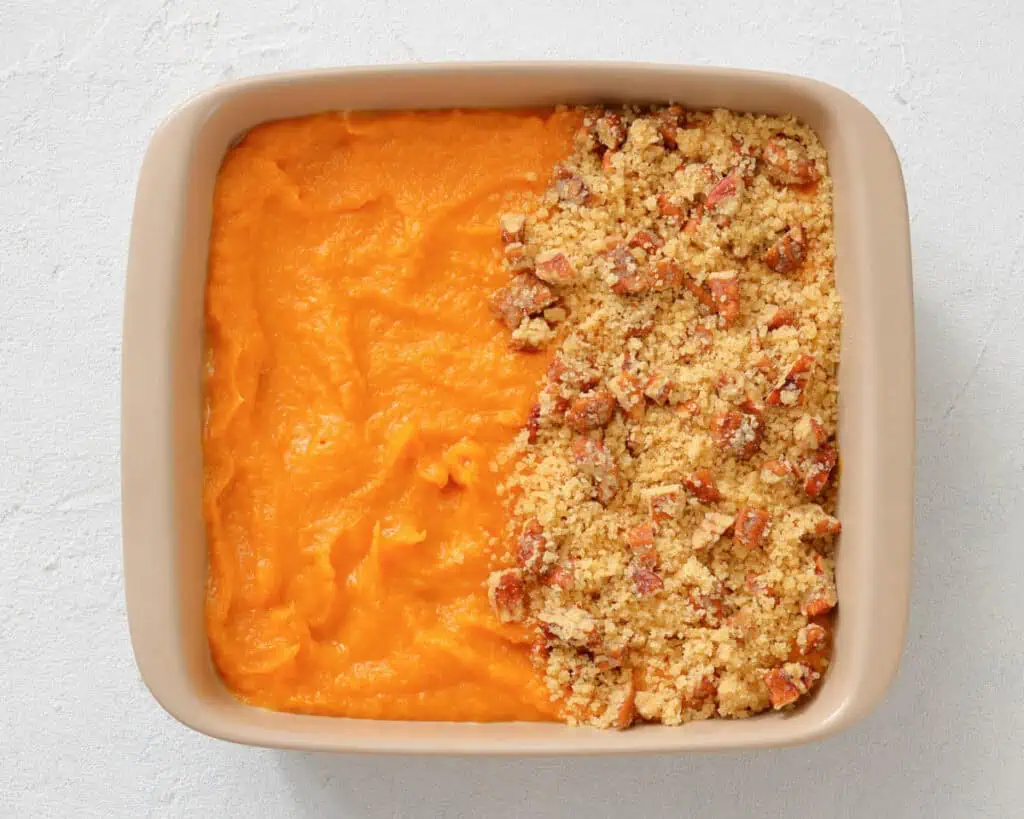 Square baking dish with half covered in smooth orange sweet potato puree and the other half topped with a crumbly pecan streusel topping.