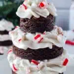 A three-tiered chocolate cake with white frosting and crushed peppermint candy, topped with a small silver star.