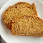 Two slices of Butternut Squash Loaf with Spiced Icing are placed on a white plate, showing a moist and dense texture with a golden-brown crust.
