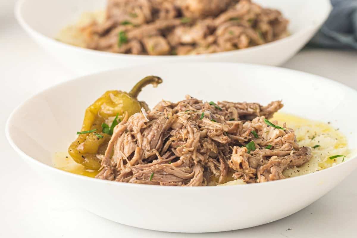 Mississippi Pork Roast garnish served over mashed potatoes in a white bowl.