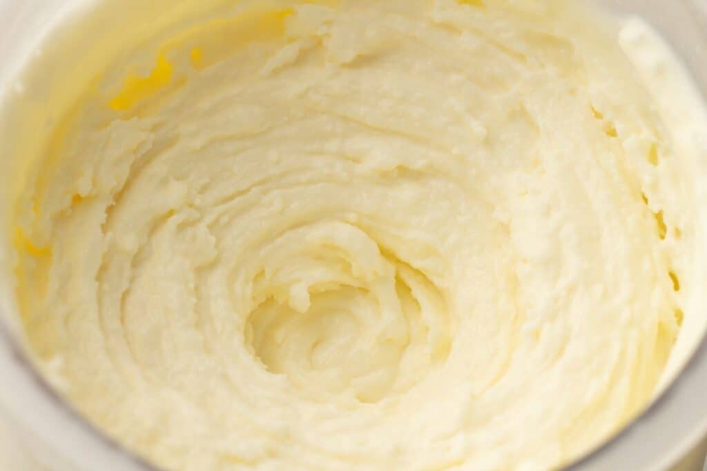 Close-up of smooth, whipped butter or cream in a mixing bowl, showing a creamy, light texture with visible swirls.