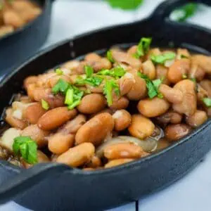 A black oval dish filled with Instant Pot Charro Beans topped with chopped cilantro.