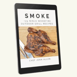 An e-book cover on a tablet displays "Smoke: 25+ Ninja Woodfire Outdoor Grill Recipes" with a grilled spatchcock chicken and utensils, authored by Chef Jenn Allen.