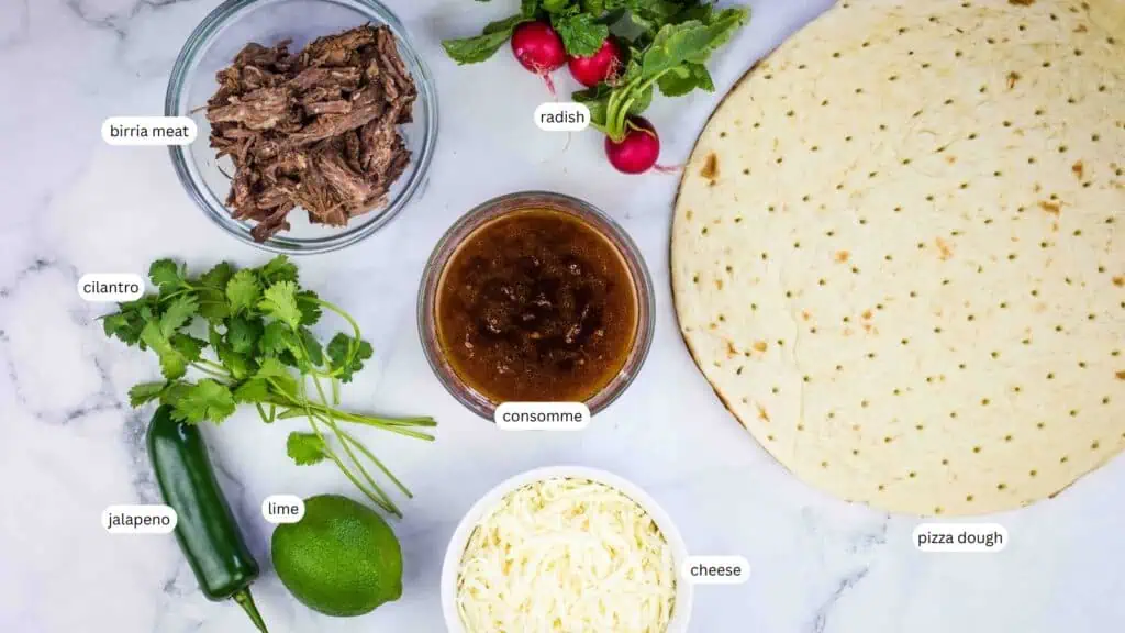 Ingredients for birria pizza laid out, including birria meat, radish, pizza dough, cheese, consommé, cilantro, jalapeño, and lime, each labeled.