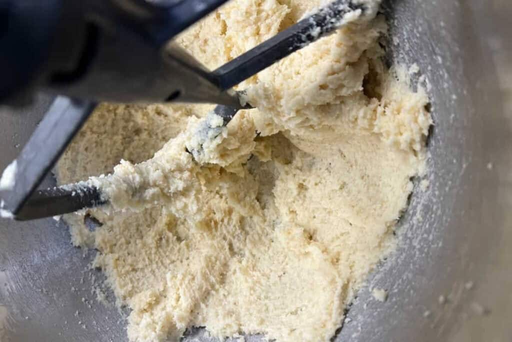 Creamed butter and sugar mixture in a metal mixing bowl with a paddle attachment.