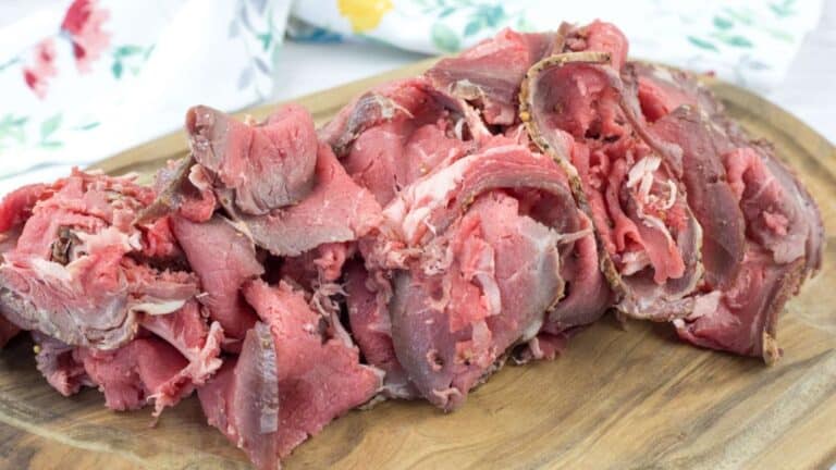 Slices of rare roast beef arranged on a wooden cutting board.