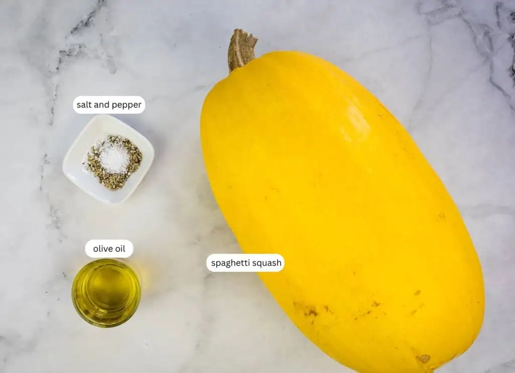 A whole spaghetti squash, a small dish of salt and pepper, and a small bowl of olive oil on a marble surface.