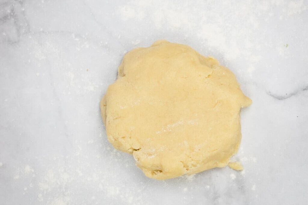 A ball of raw dough on a floured marble surface, ready for rolling or further preparation.