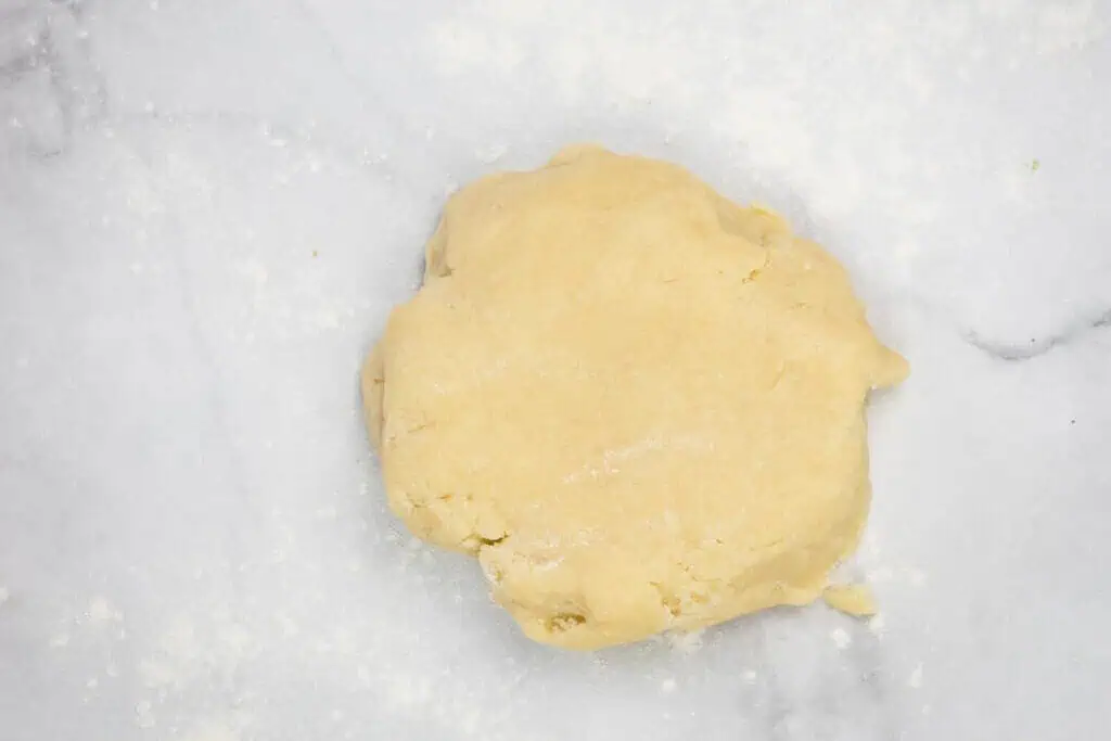 A ball of raw dough on a floured marble surface, ready for rolling or further preparation.