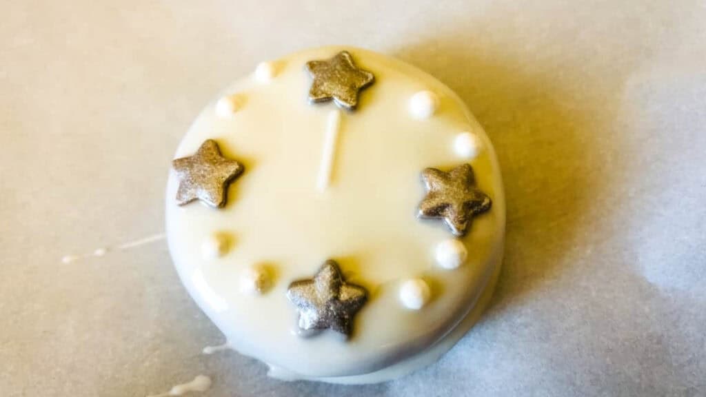 A round white treat decorated with five metallic star-shaped candies and small white candy pearls, arranged in a circular pattern.