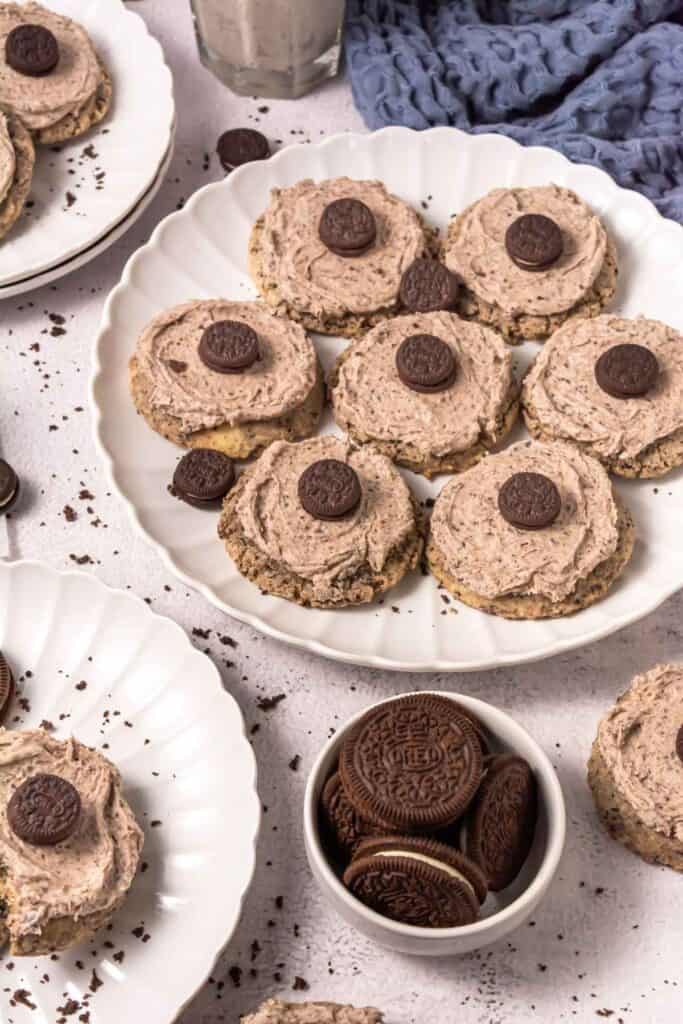 A plate of round cookies topped with chocolate cream and mini chocolate sandwich cookies, surrounded by more cookies and whole sandwich cookies in a bowl.