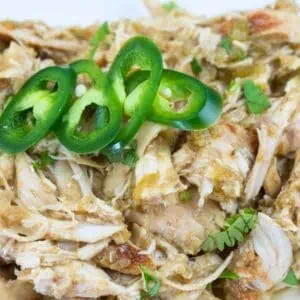 Shredded chicken with green sauce, garnished with sliced jalapeños and fresh cilantro.