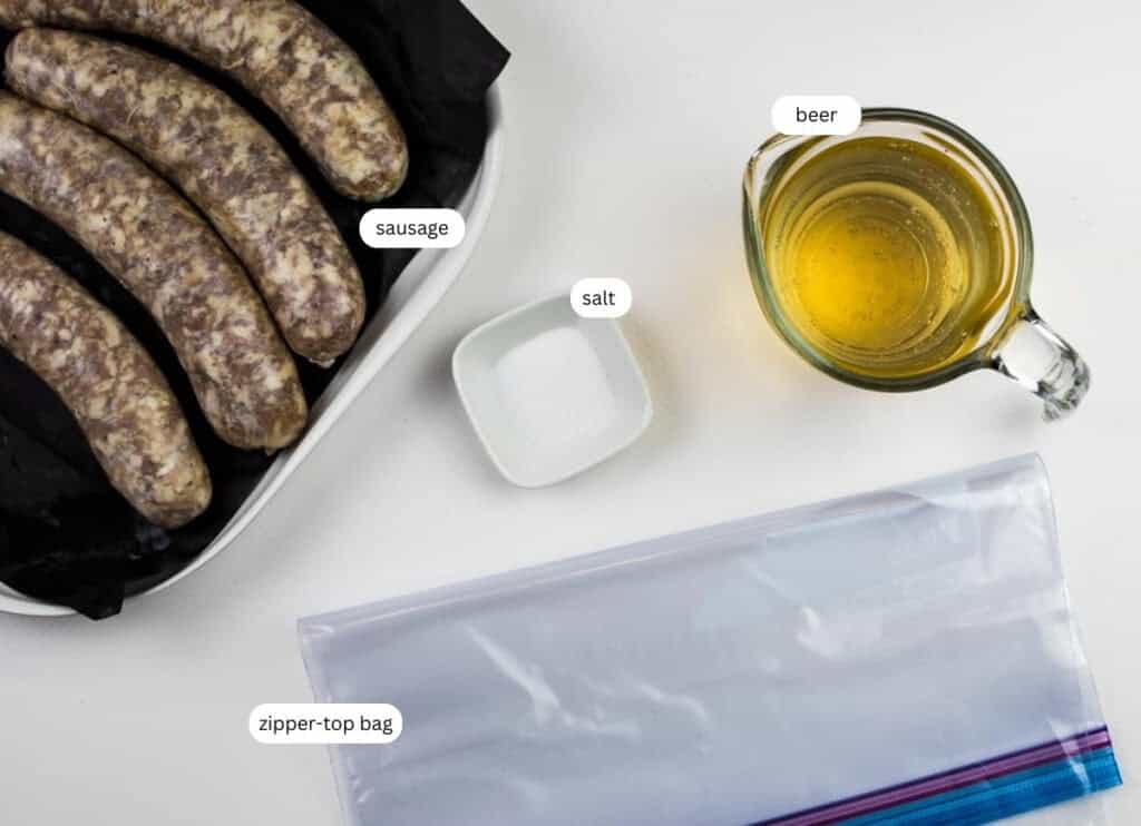 Raw sausages in a dish, a small bowl of salt, a measuring cup of beer, and an empty zipper-top bag are arranged on a white surface.