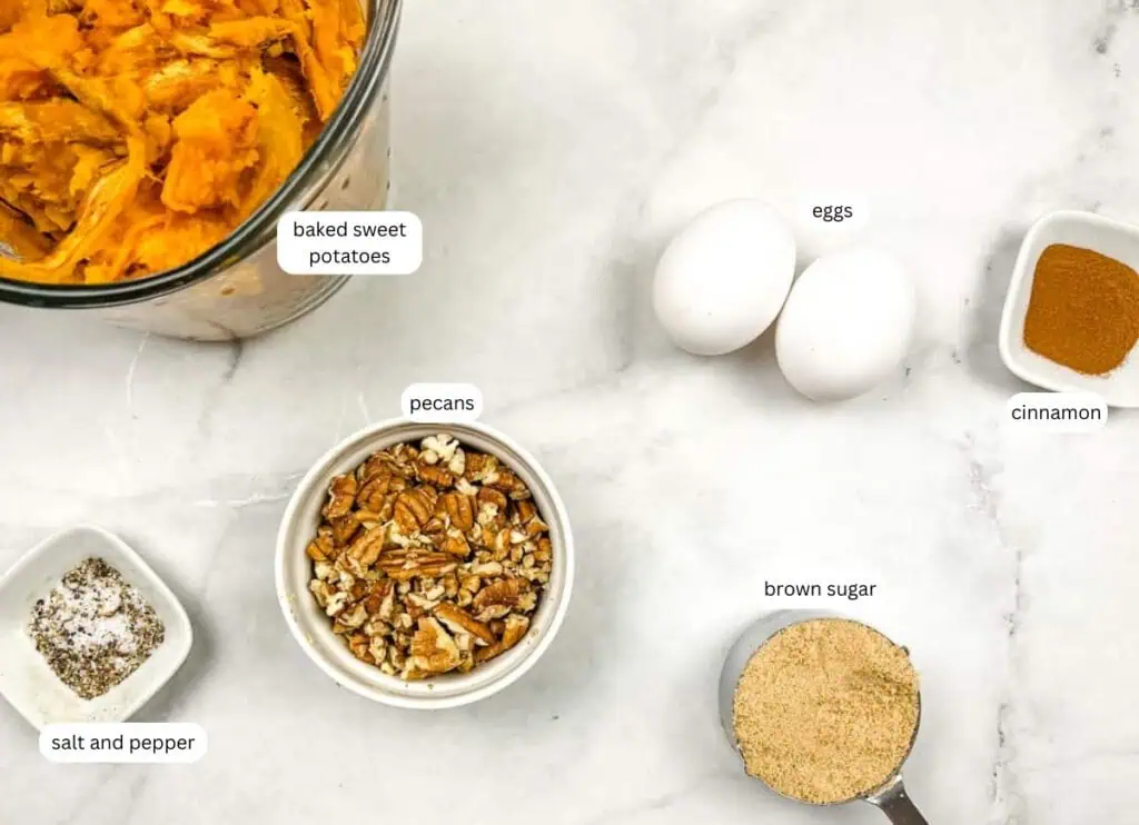 Ingredients for sweet potato casserole on a marble surface: baked sweet potatoes, two eggs, brown sugar, chopped pecans, cinnamon, and a dish of salt and pepper.