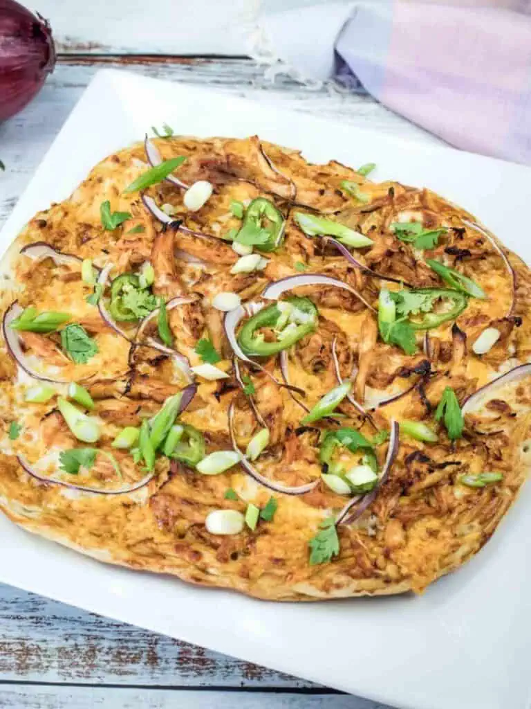 A whole BBQ chicken pizza topped with green onions, cilantro, and jalapeño.
