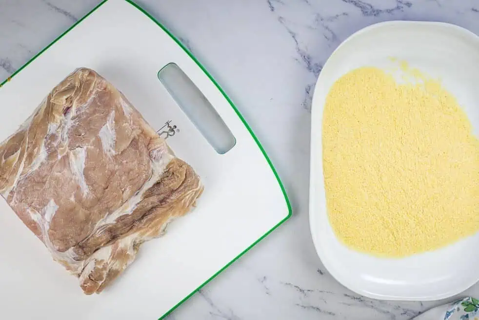 Cured peameal bacon next to a plate of cornmeal