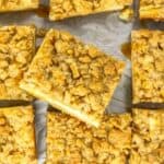 Nine oatmeal crumb bars arranged on parchment paper, with a golden brown crumb topping and visible caramel drizzle.
