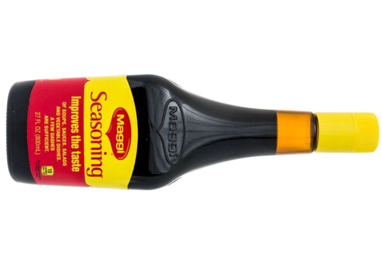 A bottle of Maggi Seasoning Sauce with a yellow and red label, lying on its side with a yellow cap.