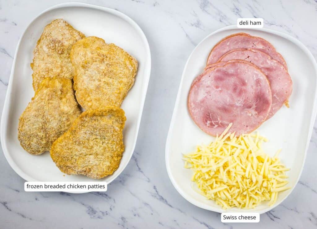 Two oval plates: one with four frozen breaded chicken patties, the other with three slices of deli ham and a pile of shredded Swiss cheese, labeled accordingly.
