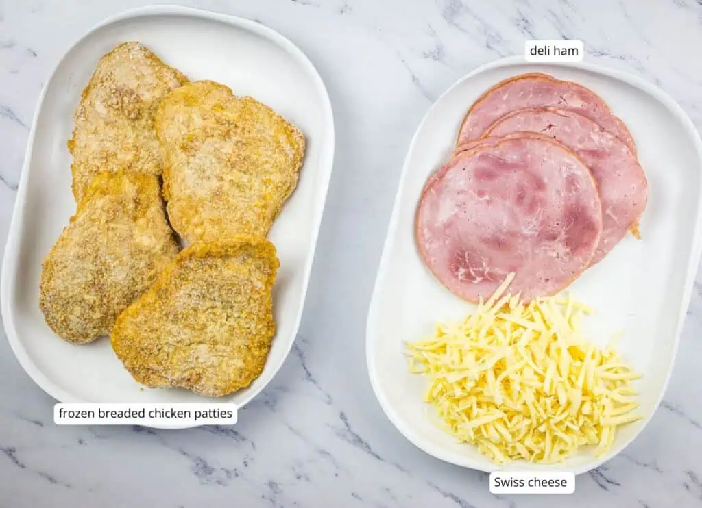 Two oval plates: one with four frozen breaded chicken patties, the other with three slices of deli ham and a pile of shredded Swiss cheese, labeled accordingly.