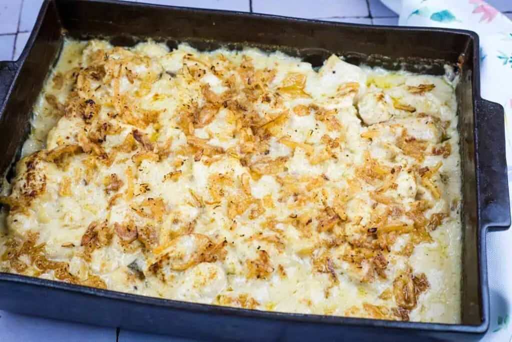 A baked casserole dish filled with creamy chicken and rice, topped with crispy fried onions.