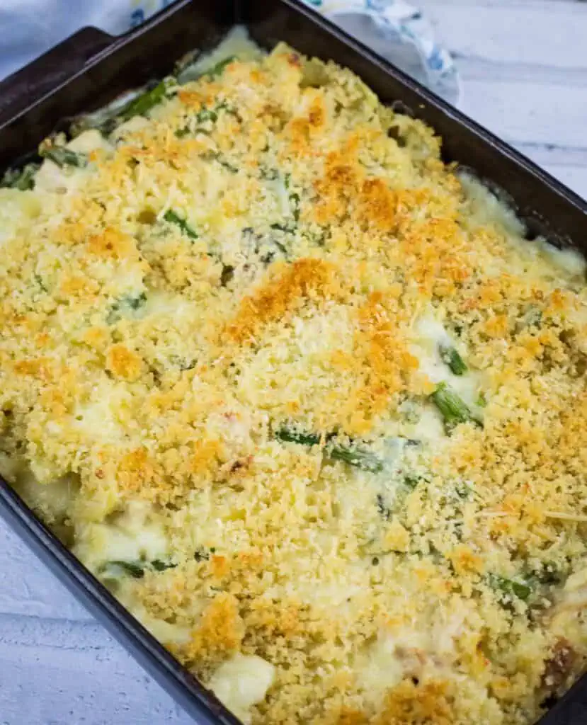 A baked casserole topped with golden brown breadcrumbs, featuring visible pieces of asparagus and a creamy filling in a rectangular baking dish.