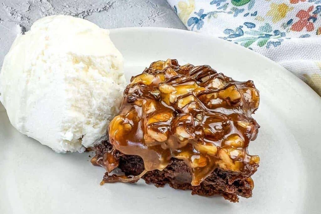 A piece of brownie with ice cream on a plate.